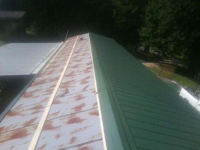 Old rusted panels beside newly installed green metal roofing — Wind Damage Roof Repair by Roofing Brothers in Lyle