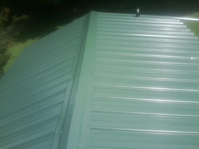 New green metal panels meeting at the ridge of a roof — Flat Roof Repair work by our crew in Lyle