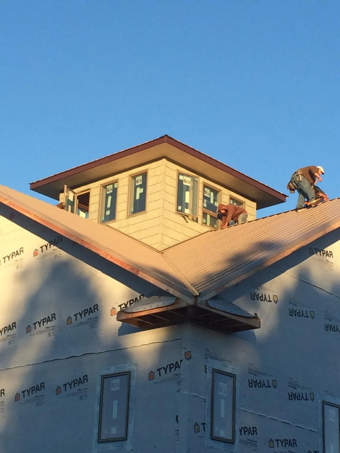 Roofers working around a rooftop cupola on a new metal roof at sunset — Roof Waterproofing in Lyle by Roofing Brothers